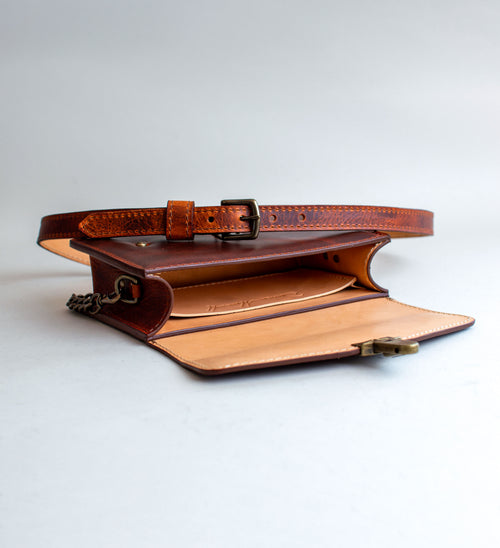 A brown leather handbag with a unique crackling effect and antique brass hardware, displayed against a neutral background.