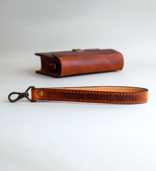 A brown leather handbag with a unique crackling effect and antique brass hardware, displayed against a neutral background.