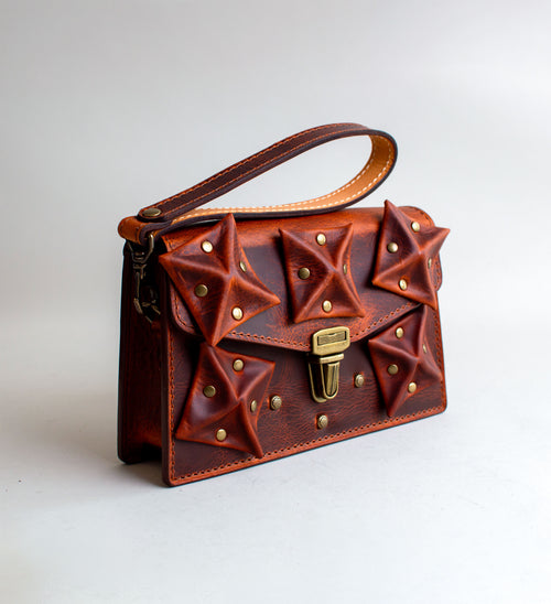 Side-View-Of-Amber-Colored-luxury-leather-handbag-with-folded-origami-leather-embellishments-handmade-in-the-us-with-brass-hardware
