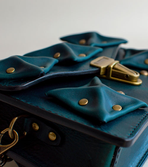 close-View-Of-Aquatic-green-Colored-Waxy-luxury-leather-handbag-handmade-in-the-us-with-brass-hardware-and-folded-origami-leather