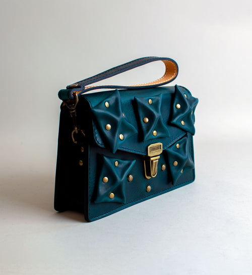 Side-View-Of-Aquatic-green-Colored-Waxy-luxury-leather-handbag-handmade-in-the-us-with-brass-hardware-and-folded-origami-leather