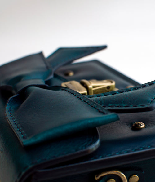 Close-up-view-of-handmade-luxury-leather-purse-with-padding-and-folded-leather-bow-featuring-antique-brass-hardware-by-Duncan-Maxwell