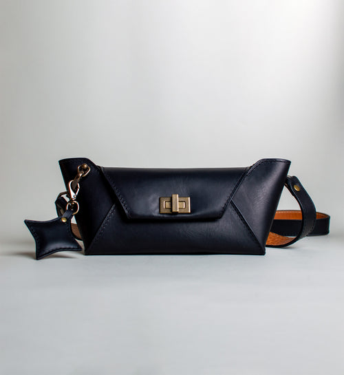 Black leather handbag with gold clasp on a light gray background