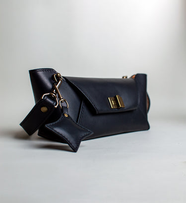 Black handbag with gold accents on a light gray background