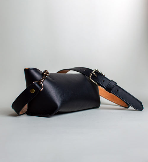Black leather bag with a strap on a light gray background