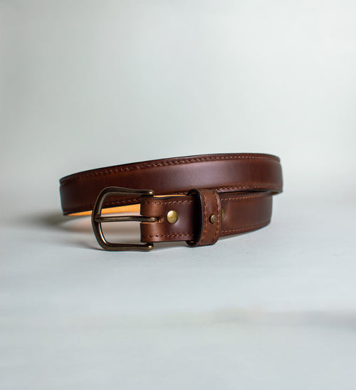 Brown leather belt with brass buckle on a light gray background