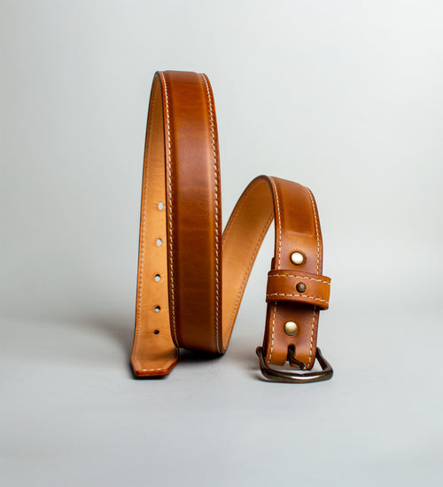 Light Brown handmade leather belt with antique brass buckle on a light gray background